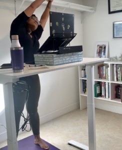 woman standing at desk doing virtual yoga