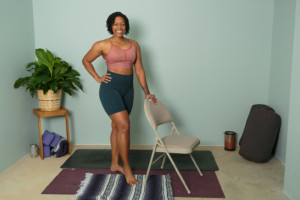 woman standing next to chair with yoga mats on the floor
