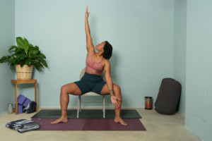 Woman sitting on chair demonstrating open twist chair yoga pose